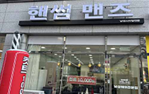 핸썸 맨즈라고  쓰여진 하얀색 간판이 붙은 건물 유리창에 컷트 10,000원 이라고 쓰여진 현수막이 걸려있다.