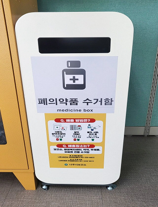 흰색 세로로 길죽한 몸통에 상단에 가로로 구멍이 나있고 폐의약품 수거함, 배출 방법은? 배출장소는? 나주시보건소 라고 적혀있는 폐의약품 전용 수거함 모습